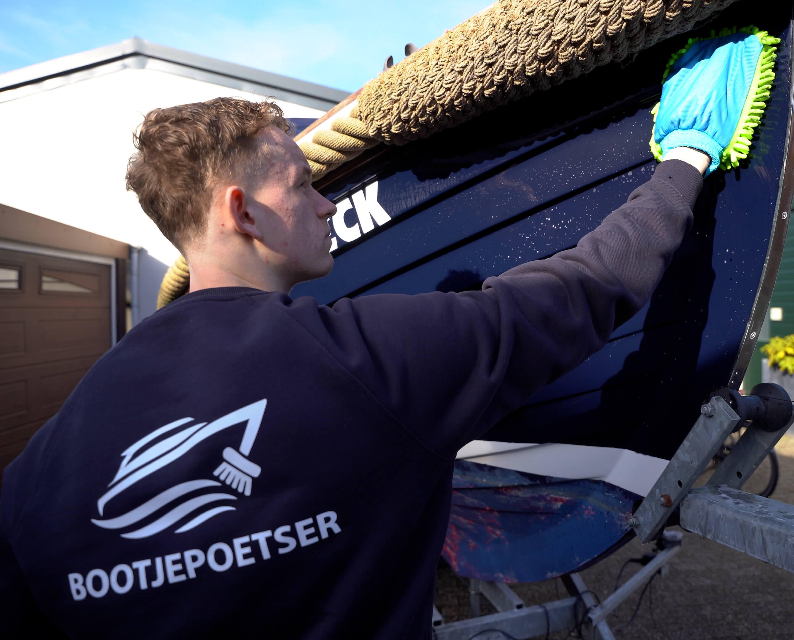 Bootjepoetser aan het werk haven Professionele bootreiniger polijst een boot op locatie in de haven