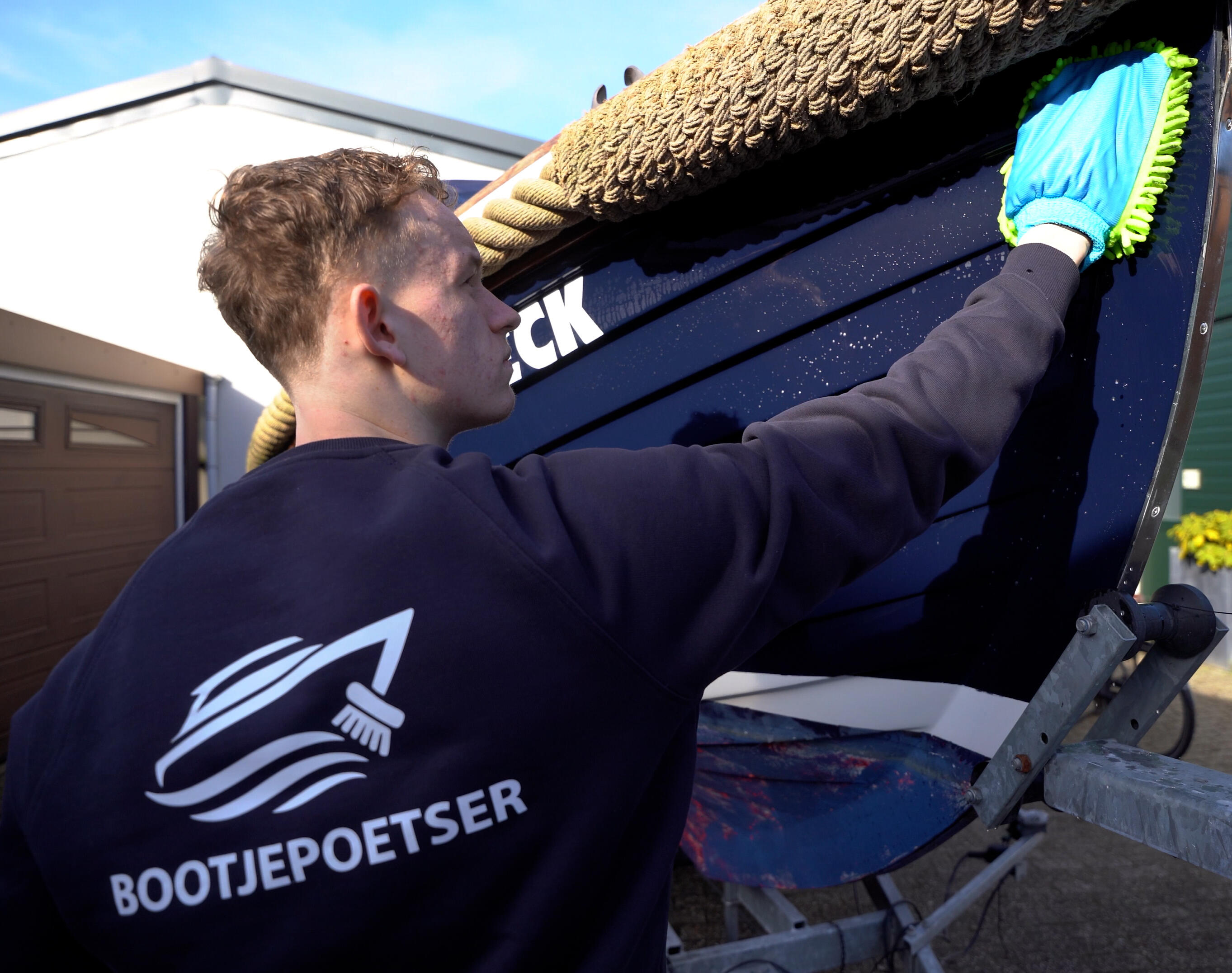 Bootjepoetser aan het werk haven Professionele bootreiniger polijst een boot op locatie in de haven